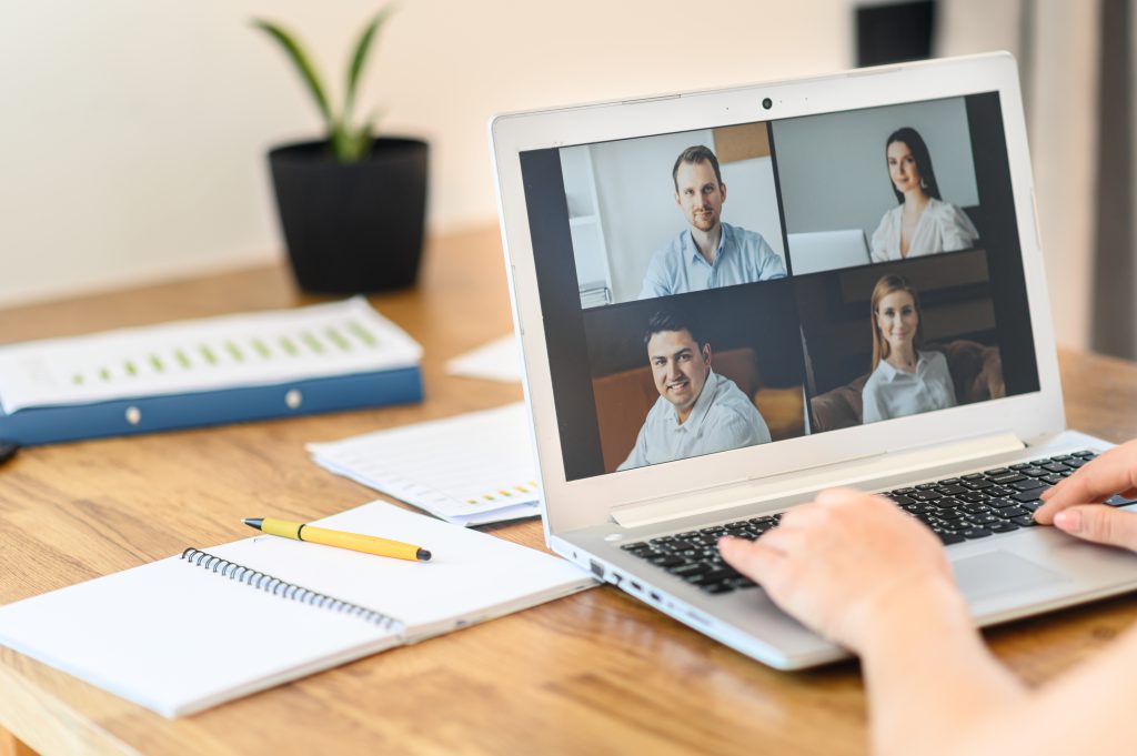 Be in touch from a distance. A laptop application for video call, video connection with many people together, webcam shots on the screen. Female hands are typing on keyboard