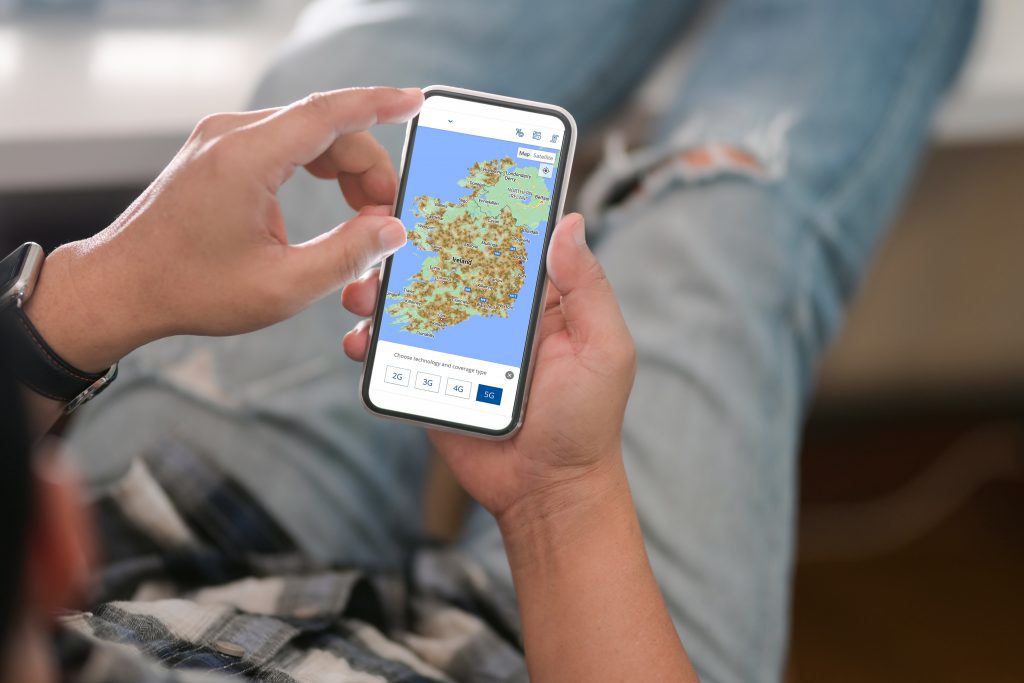 Man relaxing at home and checking ComReg outdoor mobile coverage app on his mobile phone.