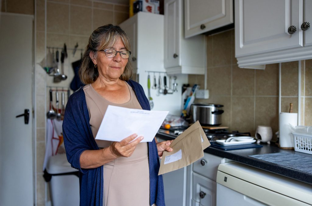 Woman opening letters in her home.