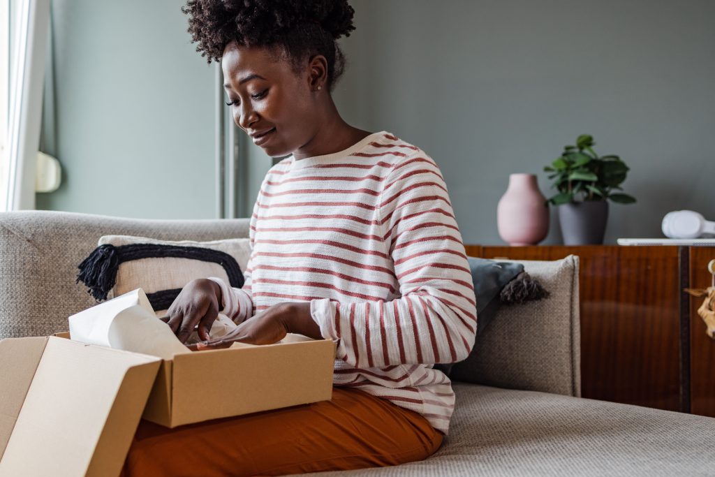 Smiling woman unpacking a parcel at home after shopping online.